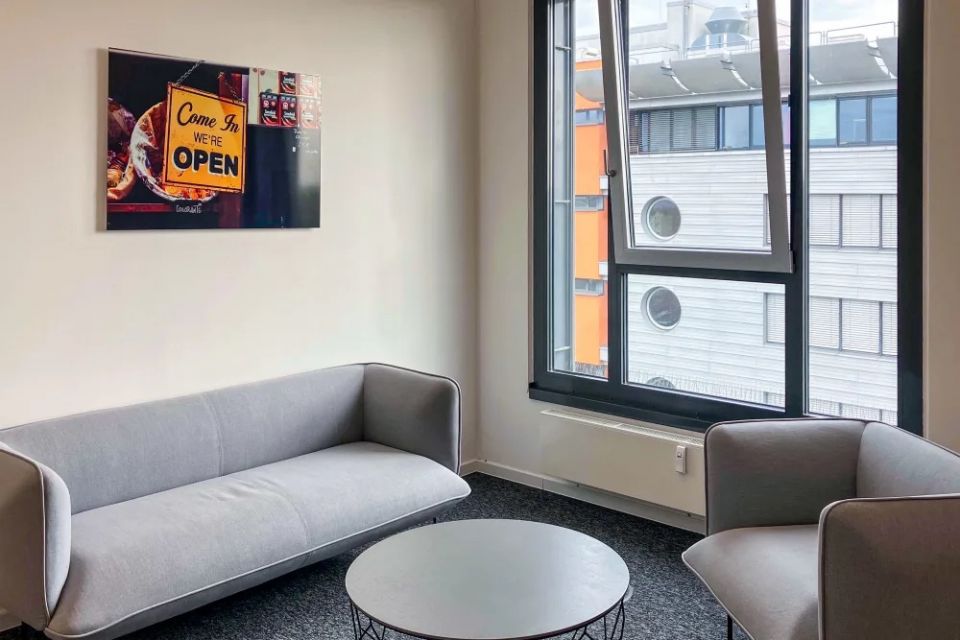 Sitzbereich mit Sofa, Sesseln, rundem Tisch und großer Fensterfront
